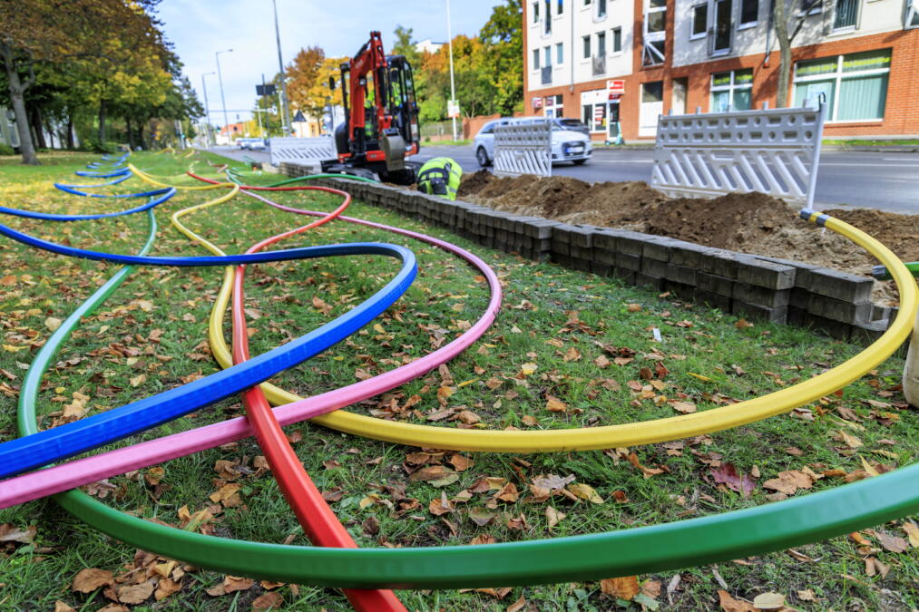 Bunte Leitungen für den Glasfaserbau auf einer Wiese.
