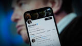 Das Twitter-Profil von Elon Musk auf einem Smartphone, im Hintergrund Musks Gesicht