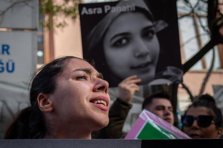 Protestierende Menschen mit einem Plakat im Hintergrund, auf dem das Gesicht von Asra Panahi abgebildet ist