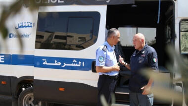 Ein palästinensischer und ein italienischer Polizeist vor einem Polizeifahrzeug.