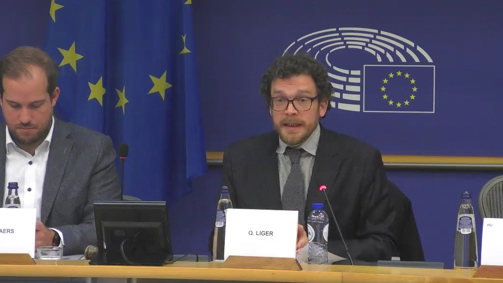 Quentin Liger sitzt neben dem Chair Jeroen Lenaers auf dem Podium.