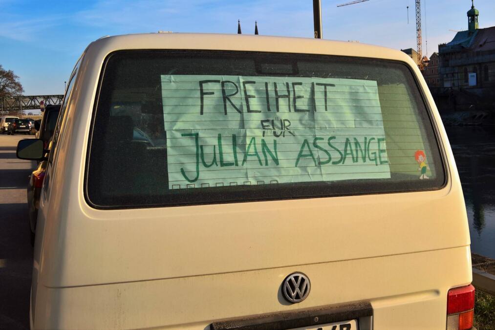 In der Heckscheibe eines VWs klebt ein Plakat mit der Aufschrift "Freiheit für Assange".