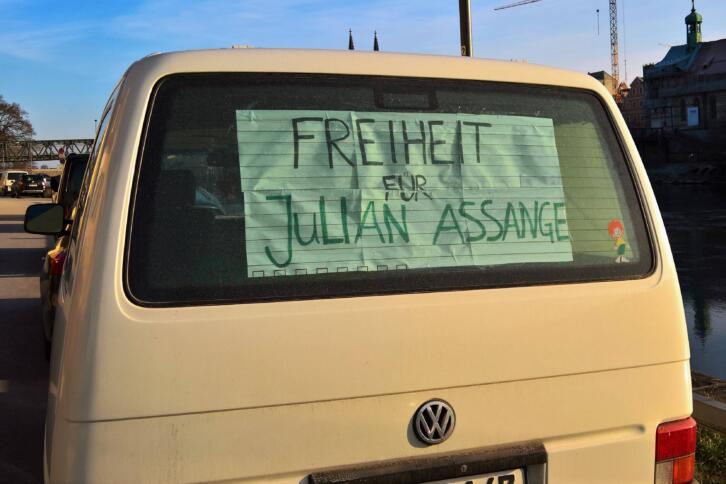 In der Heckscheibe eines VWs klebt ein Plakat mit der Aufschrift "Freiheit für Assange".