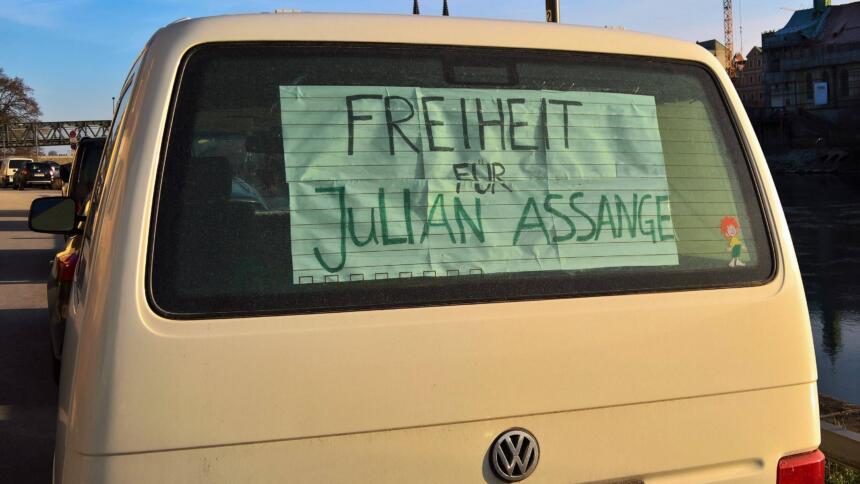 In der Heckscheibe eines VWs klebt ein Plakat mit der Aufschrift "Freiheit für Assange".