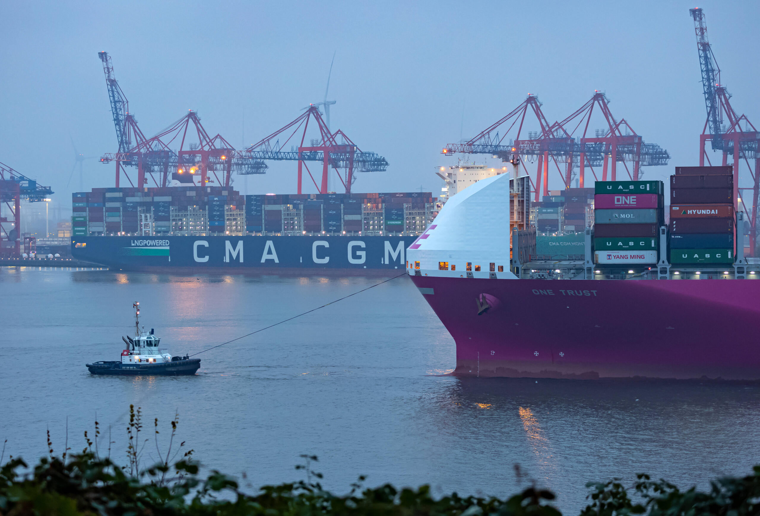 In einem Hafen liegen ein großes Schiff und ein kleines Schiff, die miteinander verbunden sind.