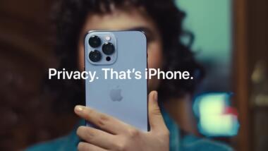 Eine Person mit kurzen, schwarzen lockigen Haaren in blauem Hemd hält ein graues iPhone in die Kamera. Davor der Schriftzug: "Privacy. That's iPhone."