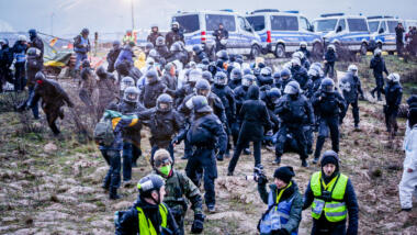 Schwarze Polizisten mit Helmen, davor Journalisten mit Warnwesten