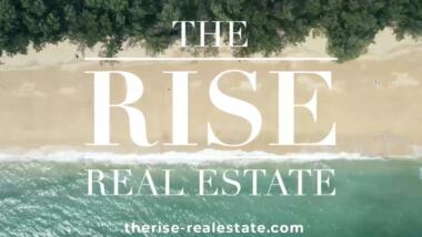 Blick von oben auf einen Strand, Schriftzug: The Rise Real Estate