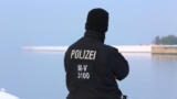 Polizist aus Mecklenburg-Vorpommern steht vor einem Hafenbecken