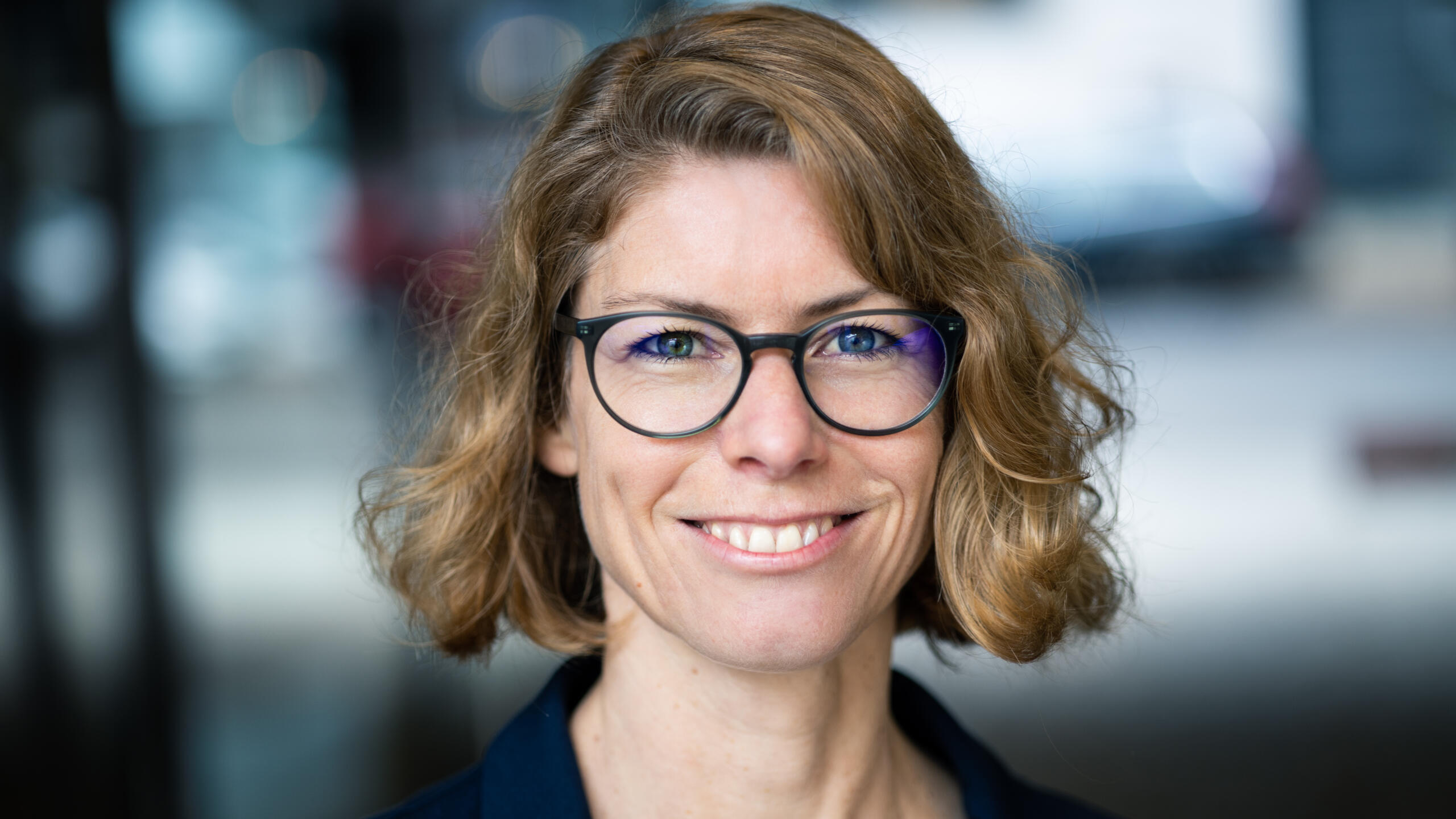 Eine lächelnde Frau mit Brille und kinnlangen Haaren