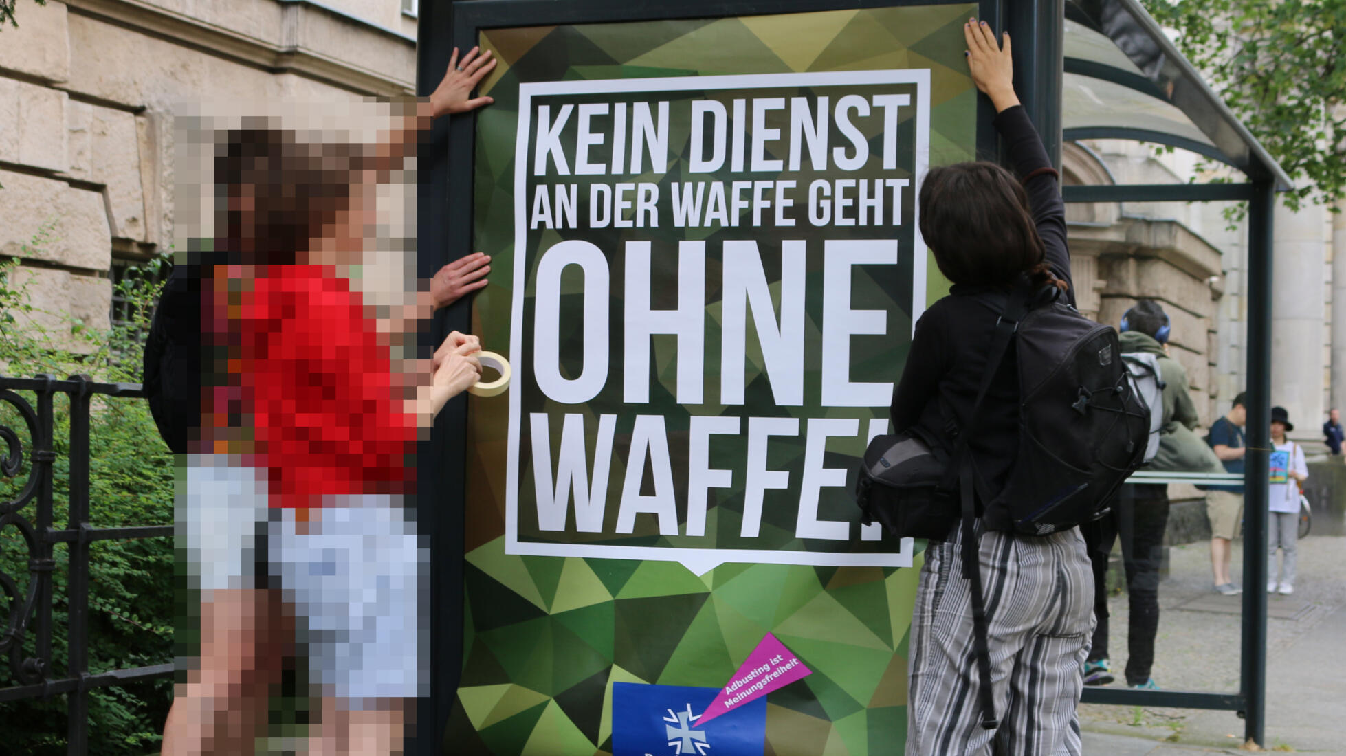 Menschen bringen Plakat in einem Plakatkasten an.
