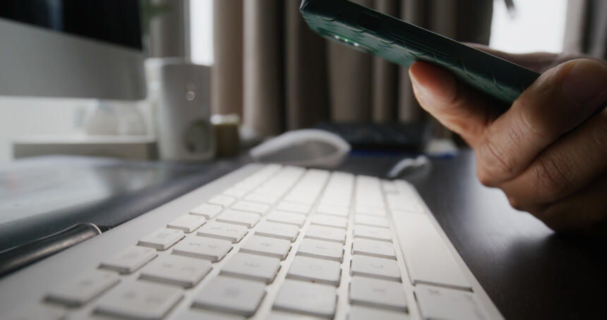 Mann benutzt Handy-Taschenlampe zur Überprüfung einer Tastatur