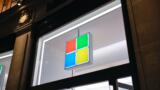 Das vierfarbige Firmenlogo von Microsoft erscheint über dem Eingang zu einem Microsoft-Store.
