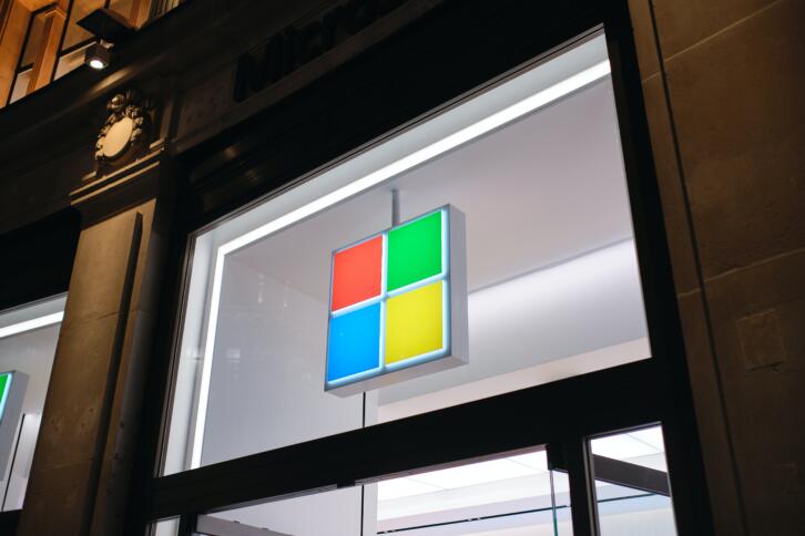 Das vierfarbige Firmenlogo von Microsoft erscheint über dem Eingang zu einem Microsoft-Store.