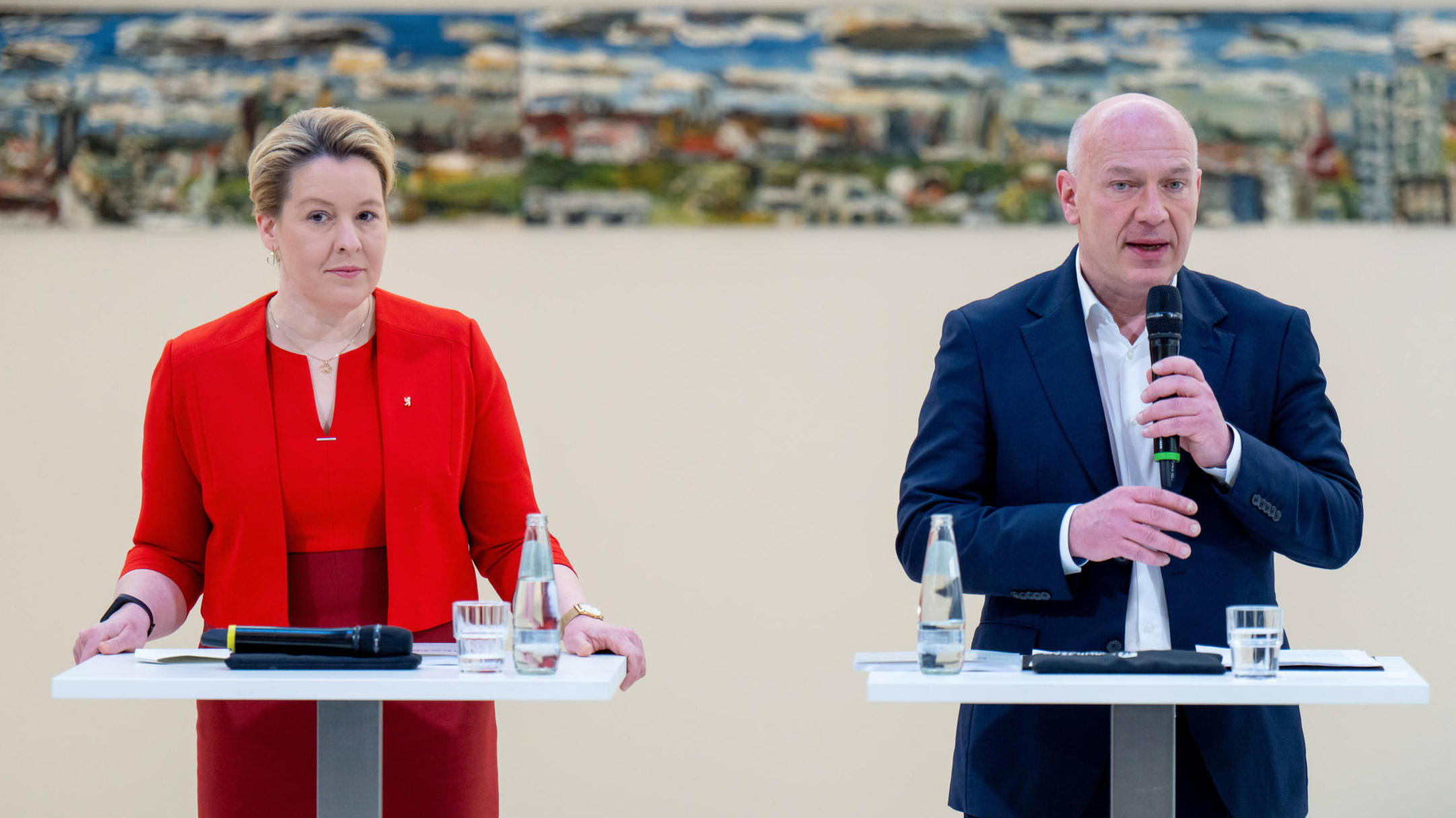 Zwei Menschen an Rednerpulten, links Franziska Giffey im roten Hosenanzug, rechts Kai Wegner im blauen Sakko