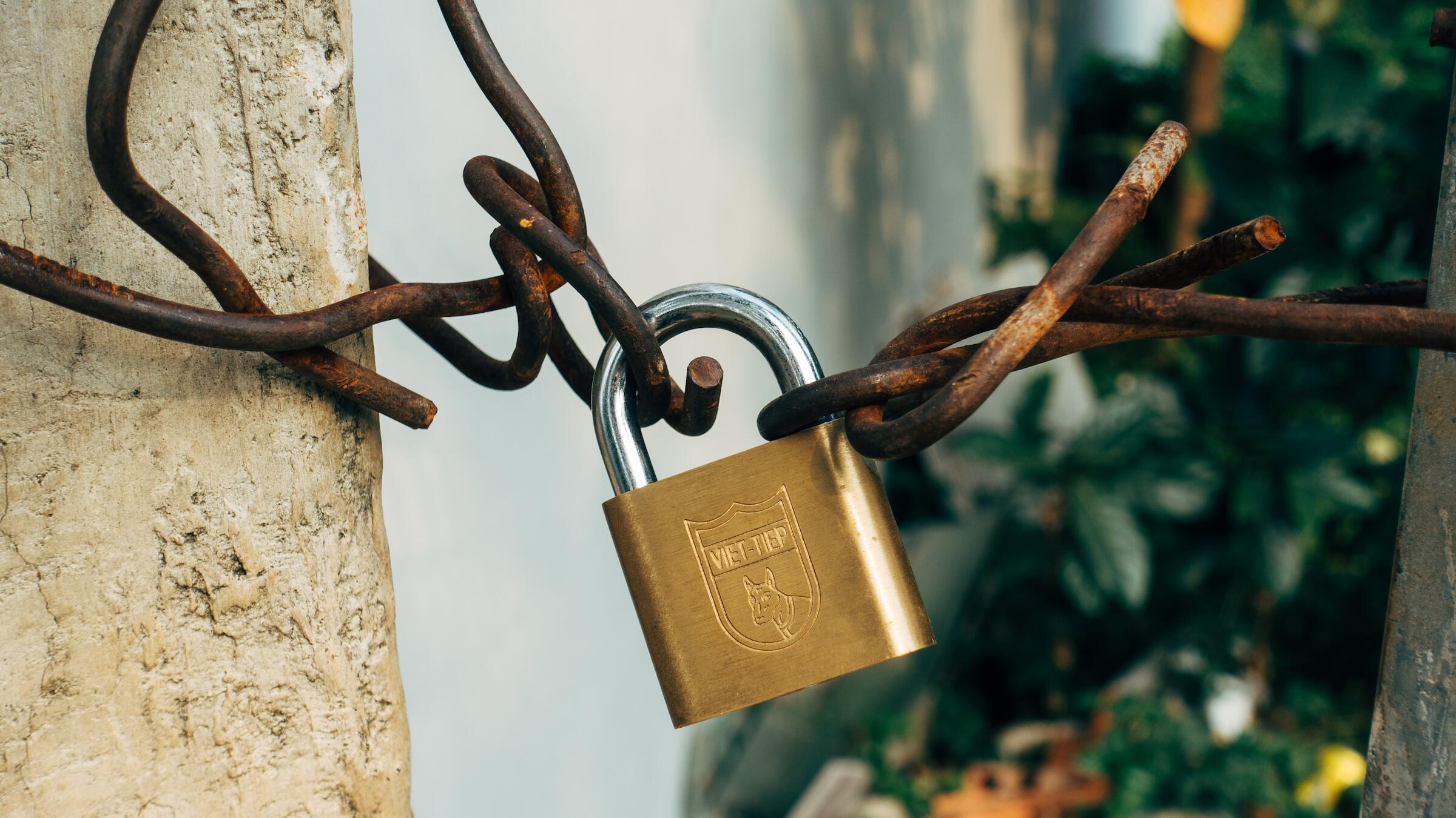 Ein Vorhängeschloss hängt an rostigen Drähten.