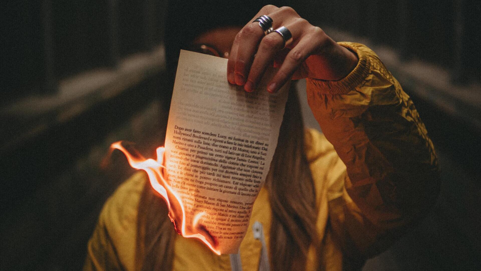 Frau hält brennendes Blatt in der Hand.
