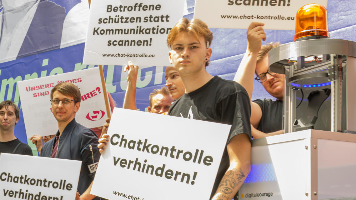 Menschen mit Protestschildern gegen Chatkontrolle