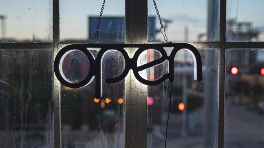 Ein Schild mit dem Schritfzug "open" vor einem Fenster