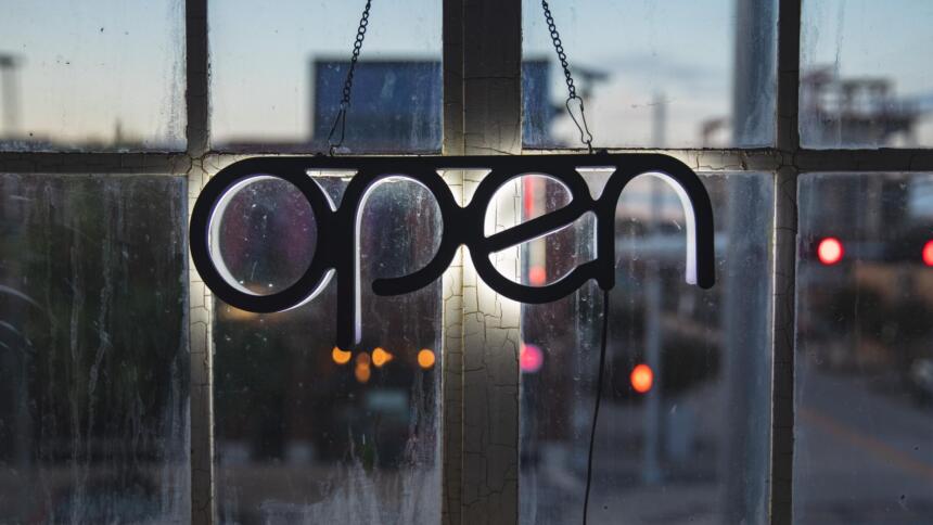 Ein Schild mit dem Schritfzug "open" vor einem Fenster