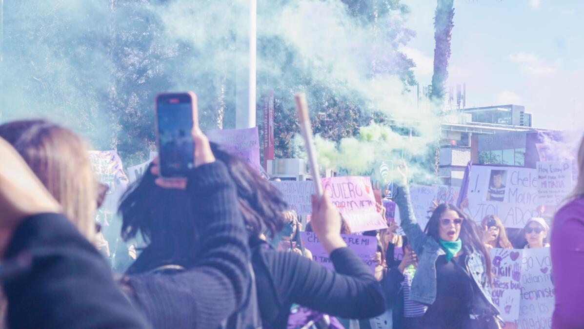 Bild eines bunten Protests, jemand hält ein Smartphone in die Luft