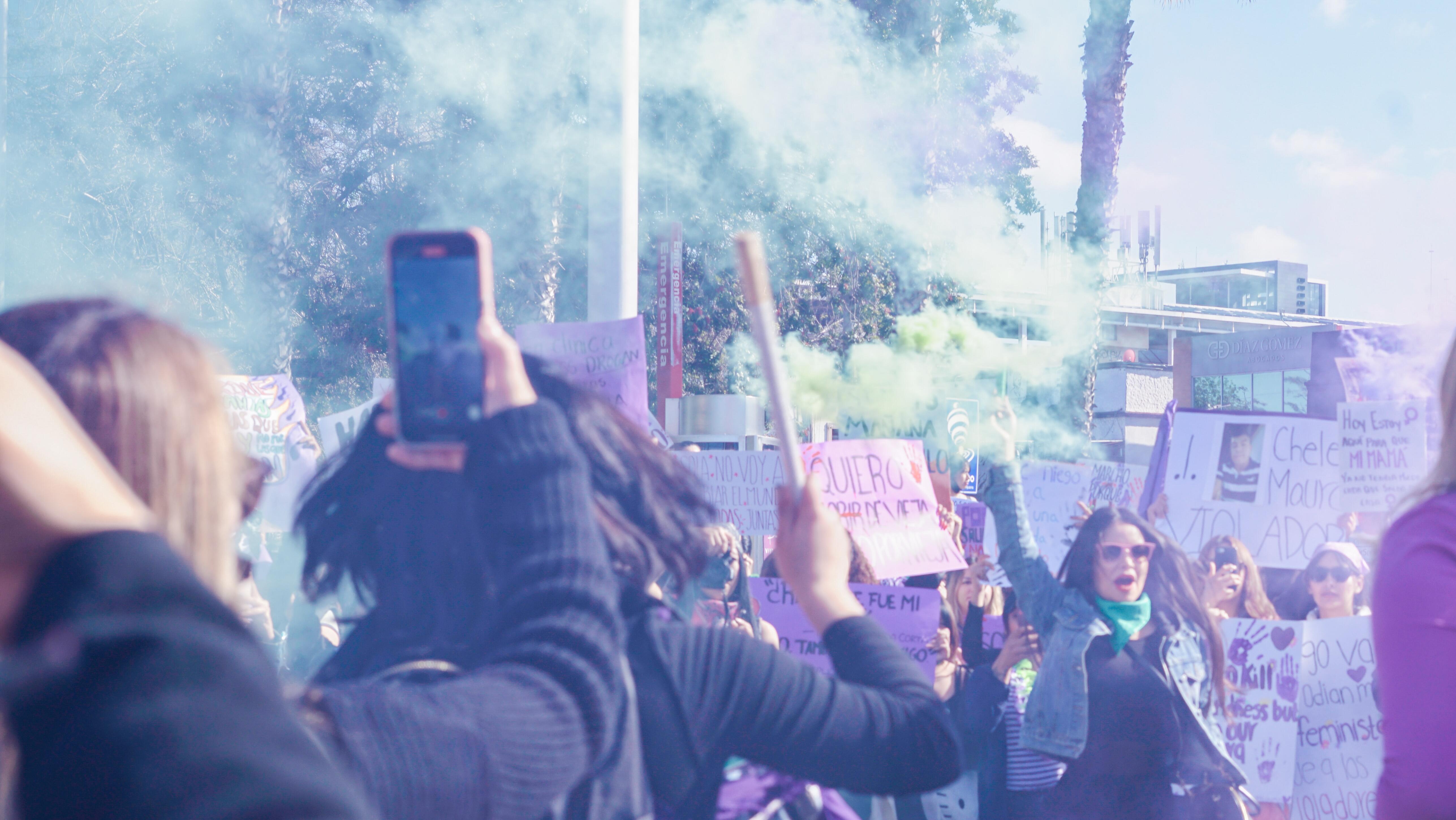 Bild eines bunten Protests, jemand hält ein Smartphone in die Luft
