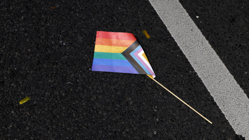 Eine Progressive Pride Flag liegt zerknickt auf dem Boden.