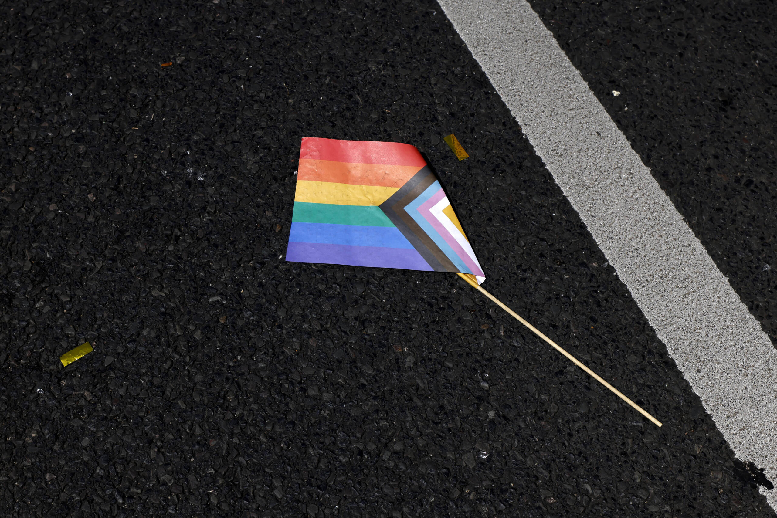 Eine Progressive Pride Flag liegt zerknickt auf dem Boden.