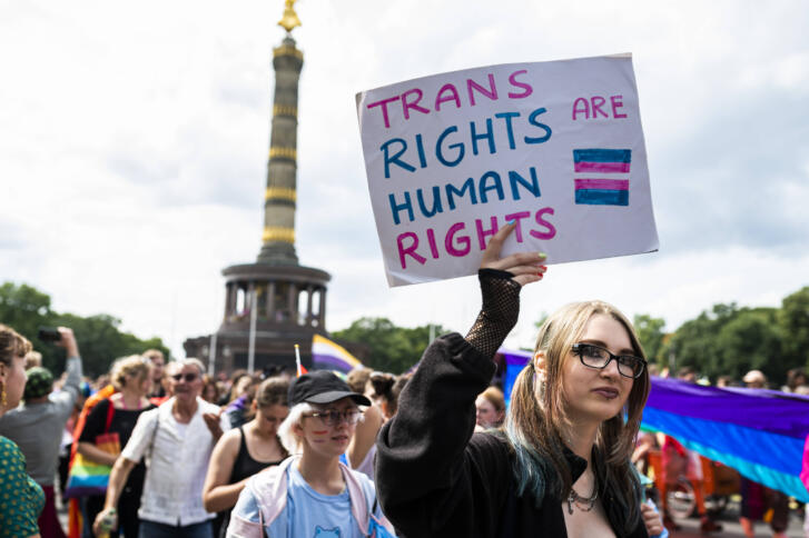 Menschen auf einer Demo vor der Siegessäule. Jemand hält ein Schild: Trans Rights Are Human Rights.