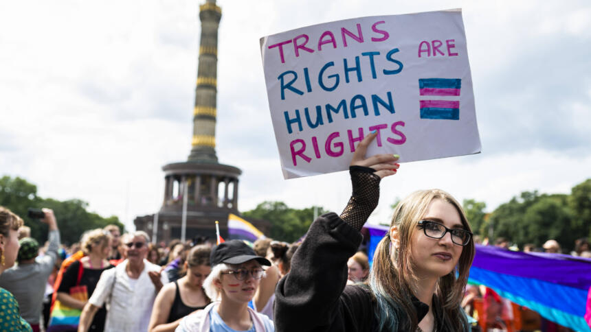 Menschen auf einer Demo vor der Siegessäule. Jemand hält ein Schild: Trans Rights Are Human Rights.