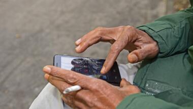 Ein Mann tippt auf einem Smartphone mit gesprungenem Display.
