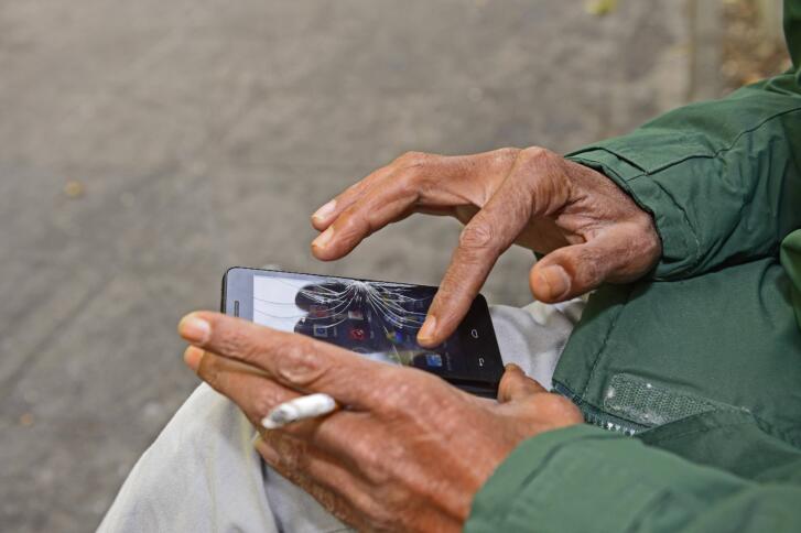 Ein Mann tippt auf einem Smartphone mit gesprungenem Display.