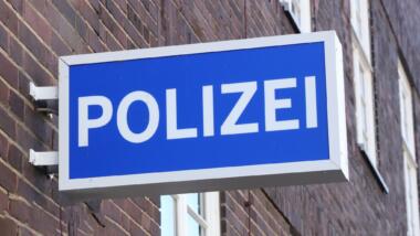 Ein blaues Schild an einer Hauswand, darauf in weißen Großbuchstaben das Wort "Polizei"