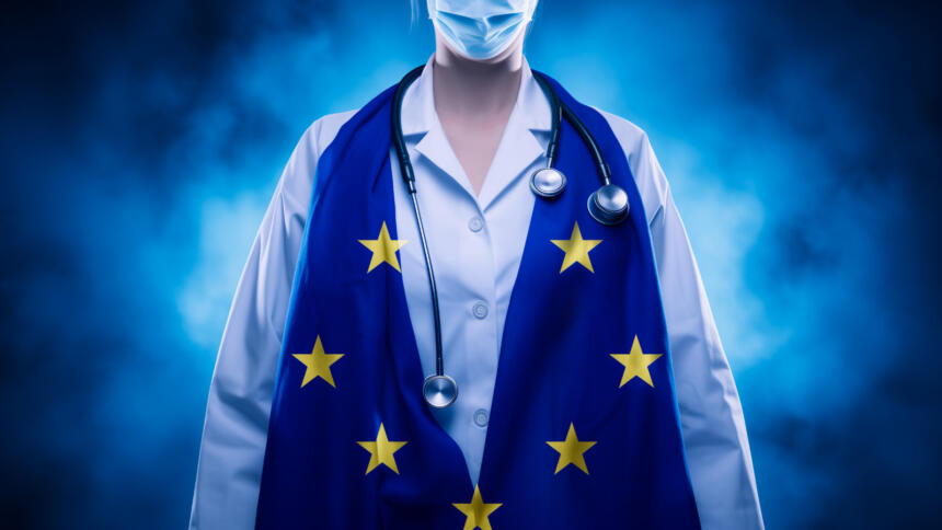 Eine Ärztin mit einem Stethoskop um den Hals, über ihrem Arztkittel liegt eine europäische Flagge