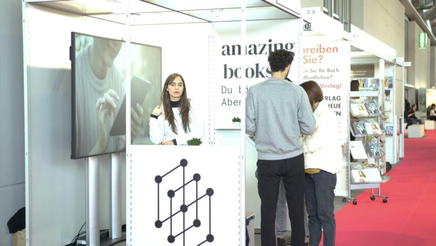 Frau steht an Messestand, Aufschrift "Amazing Books"