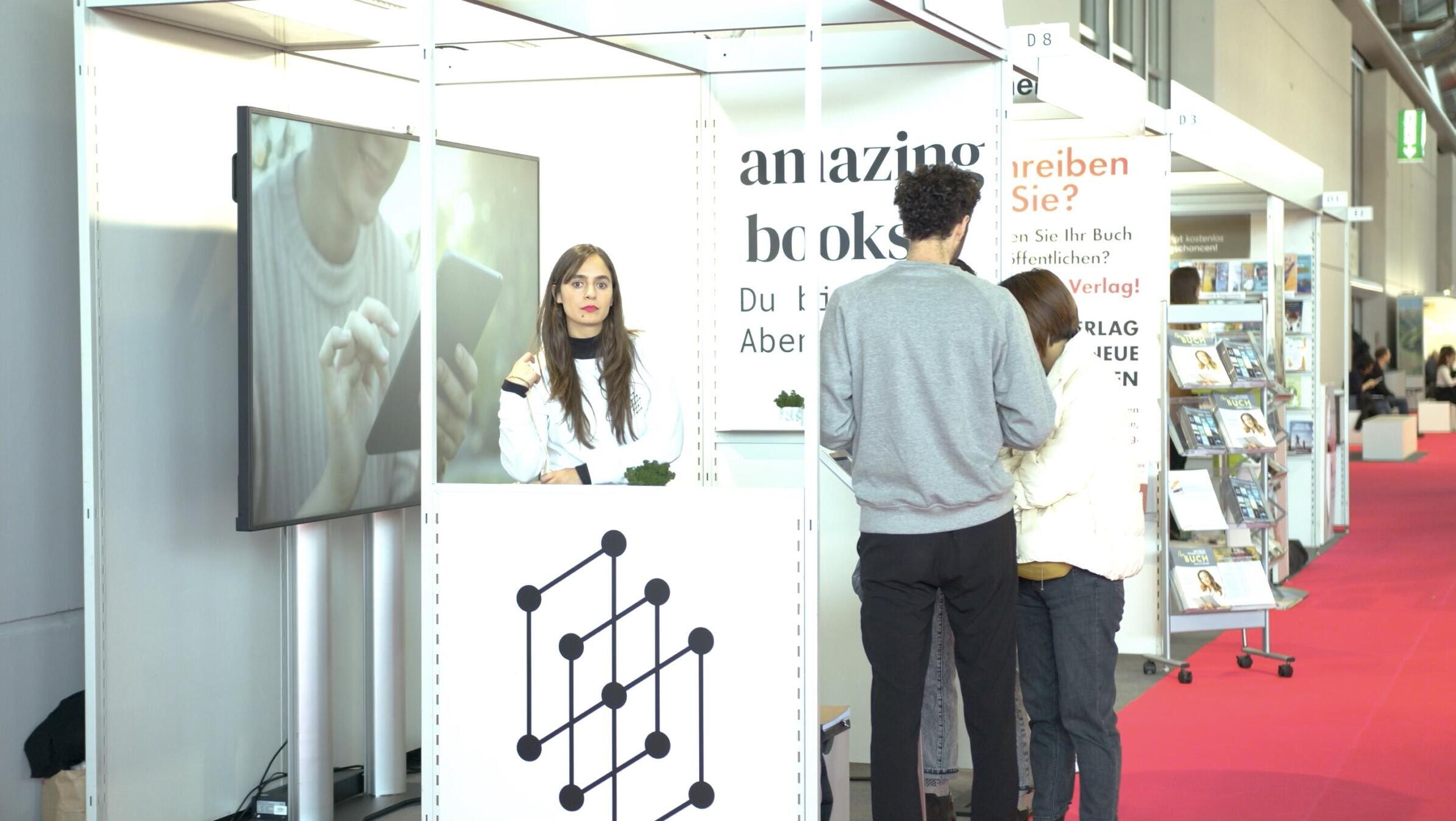 Frau steht an Messestand, Aufschrift "Amazing Books"