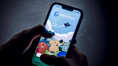 Hand hält ein Smartphone auf dem Mastodon zu sehen ist