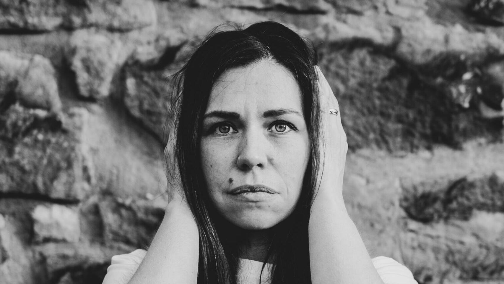 Schwarz-weiß-Foto einer Frau, die sich die Ohren zuhält
