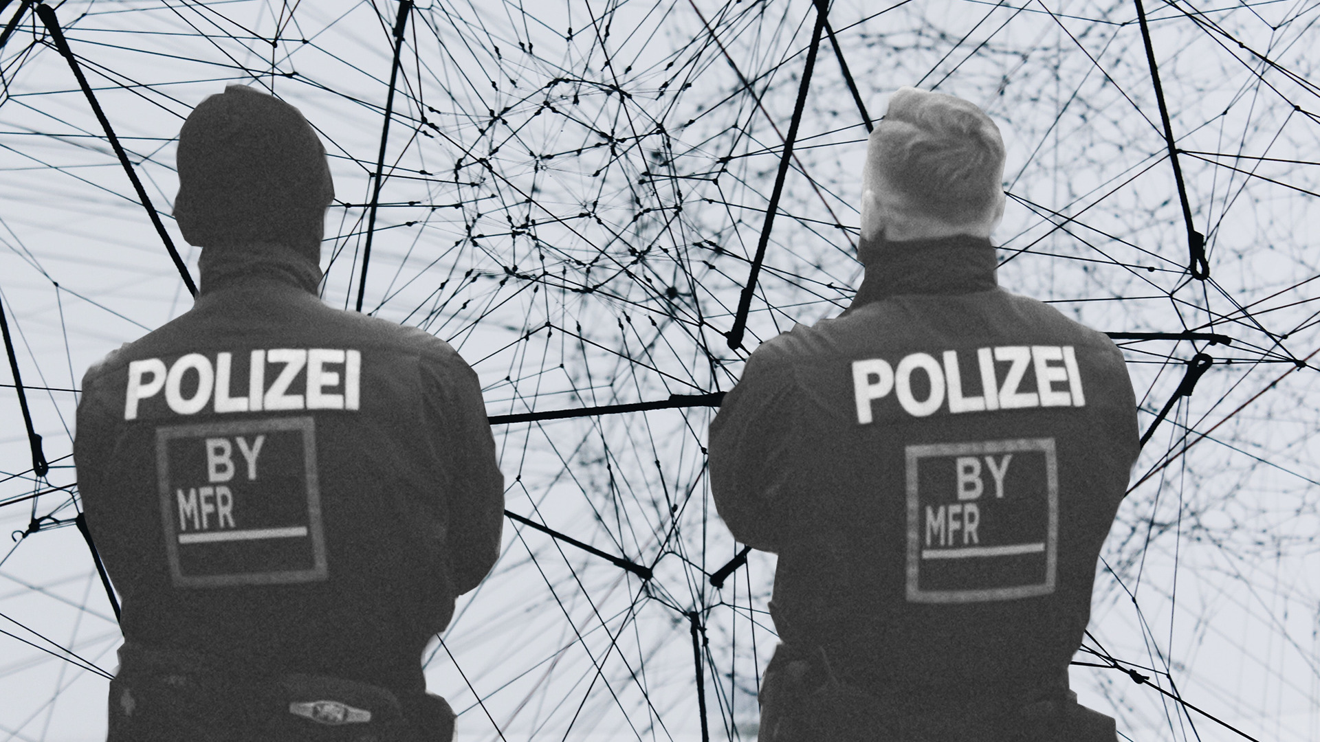 Zwei Polizisten, mit dem Rücken zur Kamera, die auf eine komplexe Linienstruktur schauen. Grautöne.
