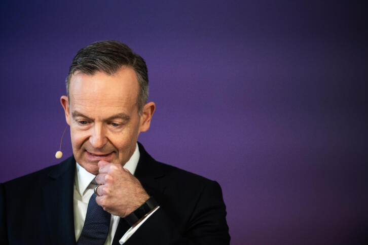 Mann im schwarzen Anzug mit Headset schaut nach unten