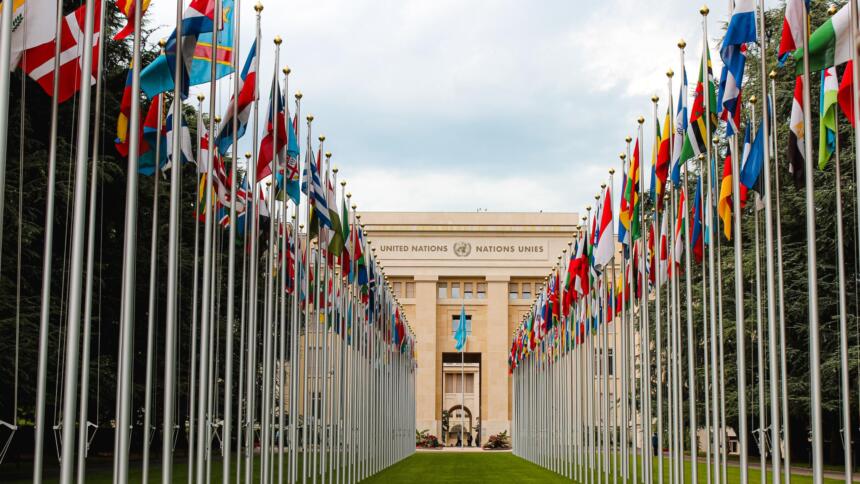 Eine Reihe mit vielen Nationalflaggen vor einem UN-Gebäude