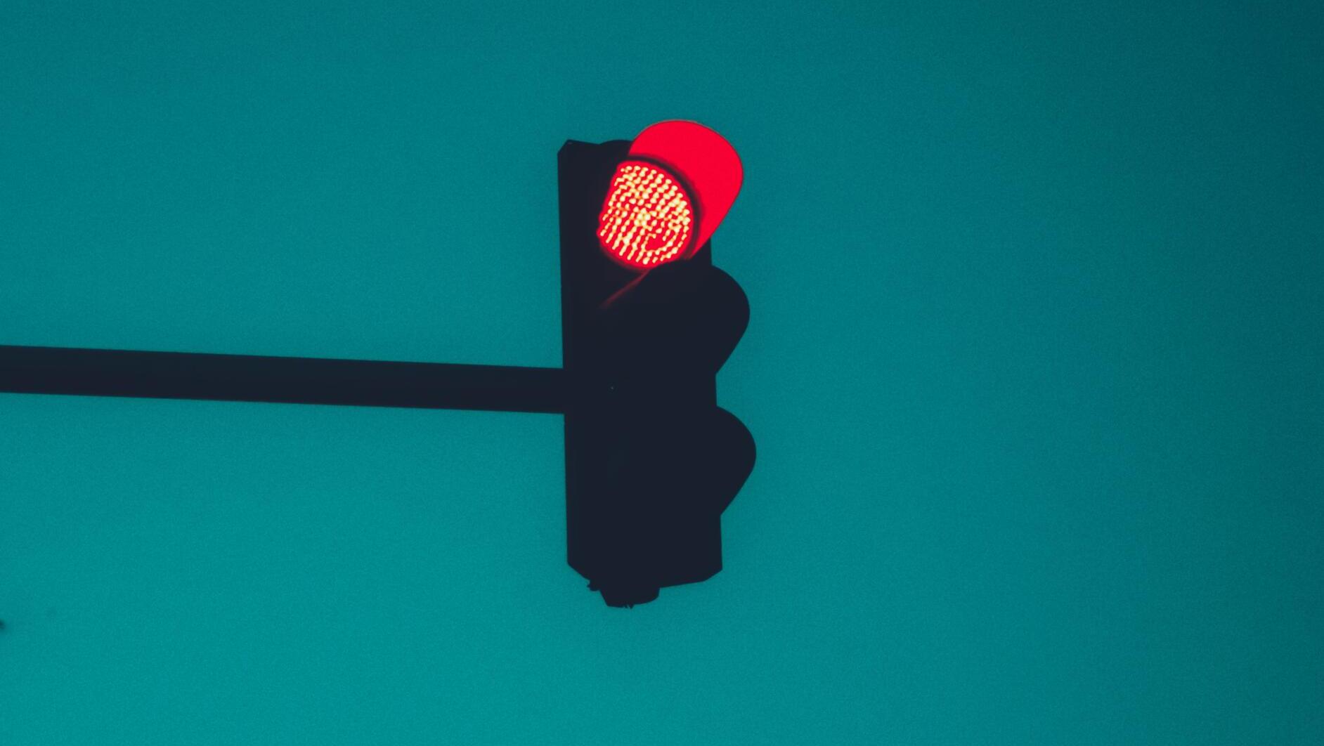 Eine rote Ampel vor blauem Himmel.