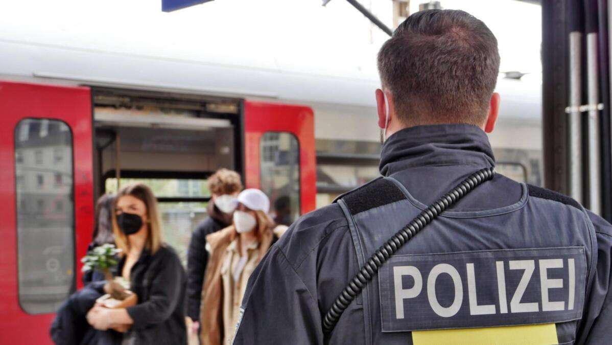 Polizist schaut auf aussteigende Personen eines Zuges.