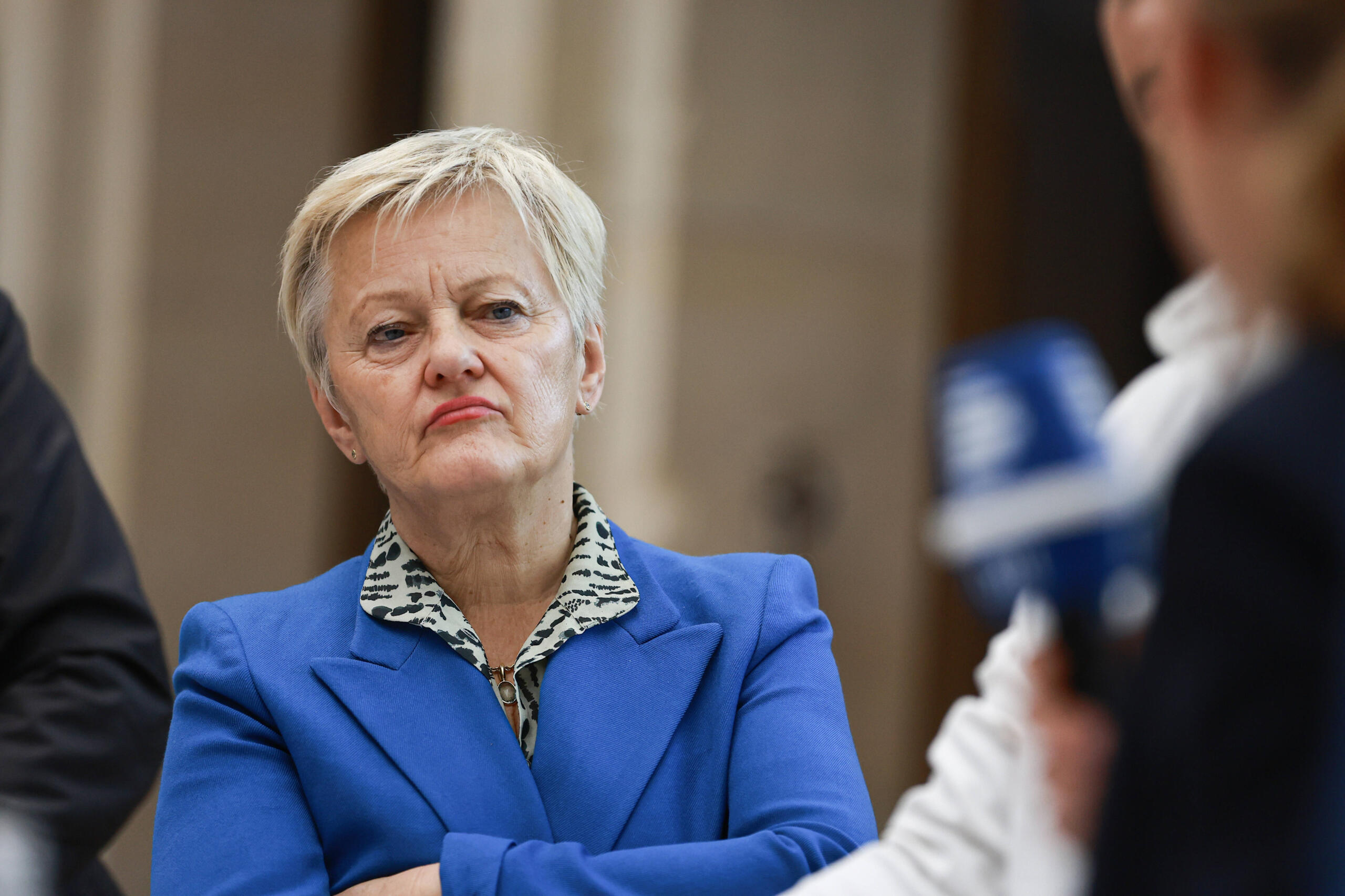 Frau mit blauem Blazer und kurzen grauen Haaren mit gekreuzten Armen