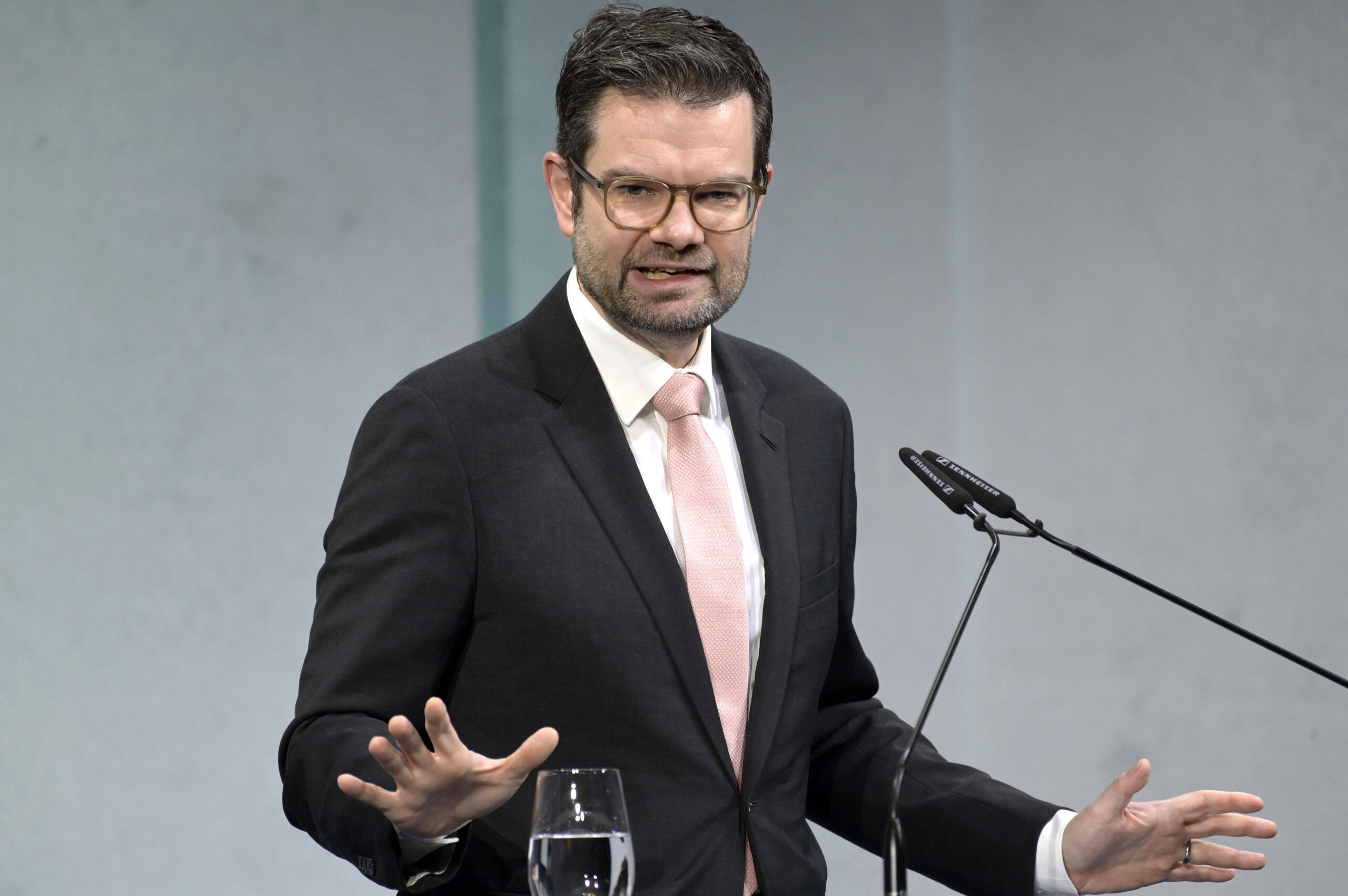 Mann mit Brille in dunklem Anzug am Rednerpult