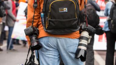 Ein Reporter von hinten, mit unmgehängten Kameras