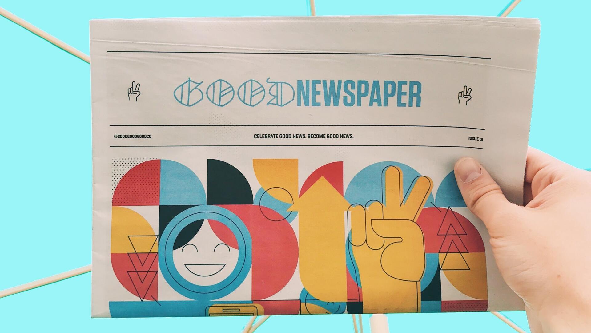 Eine Hand hält eine sehr bunte Zeitung