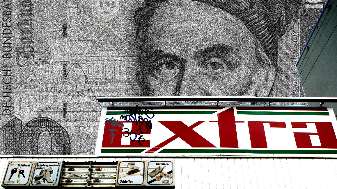 Ein Reklameschild für den Extra-Supermarkt, im Hintergrund ein 10-DM-Schein