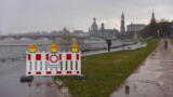 In Dresden steht vor einem Weg an der Elbe eine rot-weiße Absperrung mit dem Schild "Hochwasser"