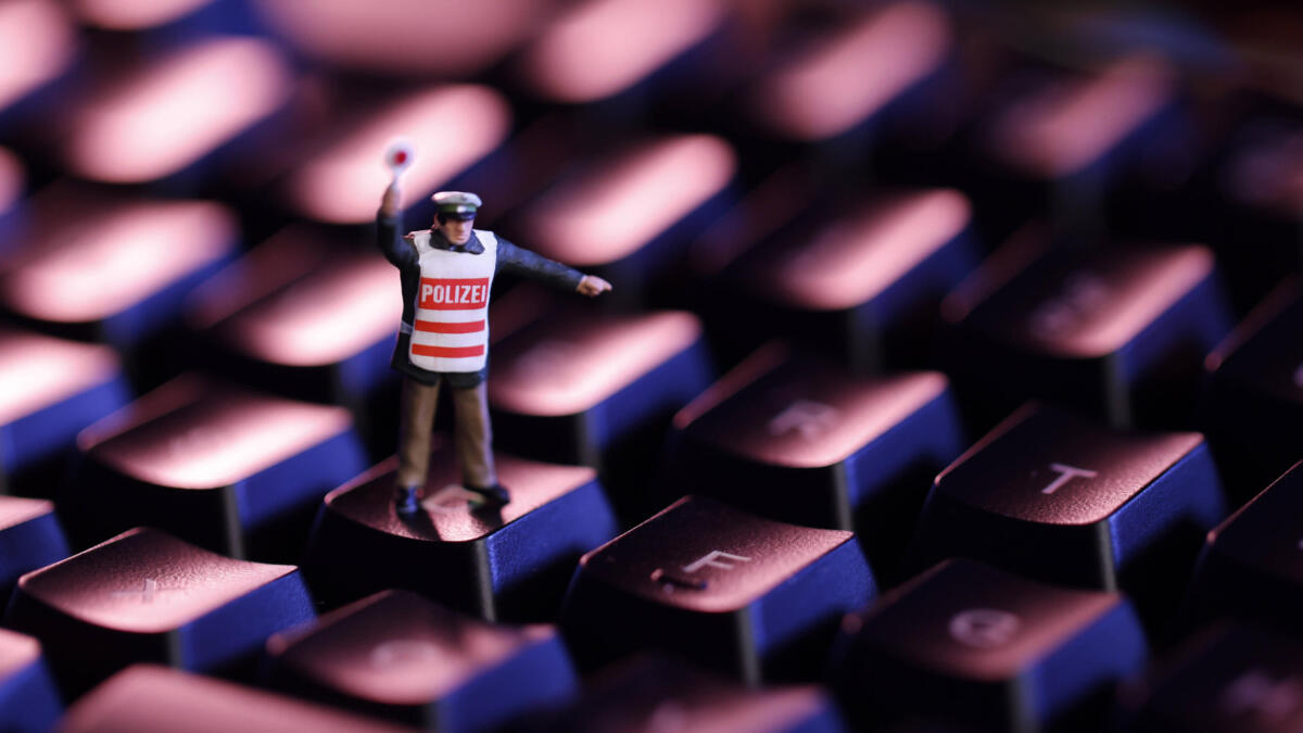 Ein Polizist steht auf einer Computer-Tastatur.
